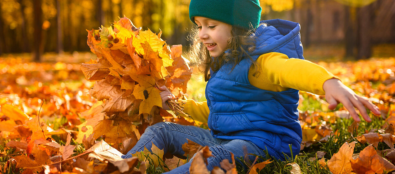 schöner Herbstanfang Kind spielt im Laub 